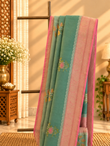 A shaded green muga georgette saree with meenakari floral bootas and a contrast pink kanni