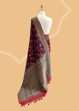 Brown Floral Tussar Georgette Benarasi Saree. Handwoven by skilled weavers at Roliana, this saree features vibrant flowers in fiery red and orange, making it a true statement piece. With a bold red blouse included, this saree is perfect for any special occasion. Shop the best collection of authentic, handwoven, pure benarasi sarees with Roliana New Delhi