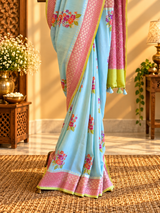 A fresh powder blue muga georgette saree with meenakari floral bootas dismissed off with a pink border and a fresh lime green kanni
