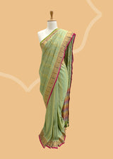 A pista green vertical stripe zari woven saree in dull gold with a vibrant meenakari paithani border and a hand-painted stripe pallu in multicolour..  Shop the best collection of authentic, handwoven, pure benarasi sarees with Roliana New Delhi