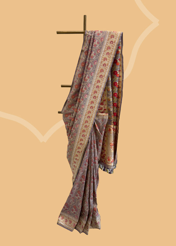A lavender tissue by silk saree with a mehraab Meenakari design all over the body and border in zari and contrast maroon colour. Shop the best collection of authentic, handwoven, pure benarasi sarees with Roliana New Delhi