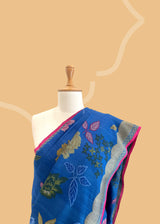 An electric blue Tussar Georgette saree by Roliana. Intricately handwoven with a beautiful contrast pink brocade blouse. Perfect for wedding and trousseau saree Shop the best collection of authentic, handwoven, pure benarasi sarees with Roliana New Delhi