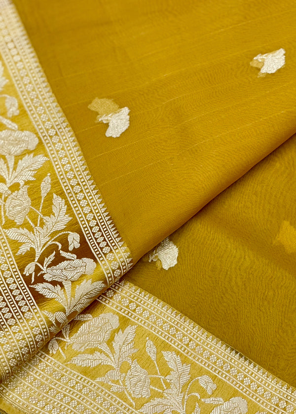Ochre yellow organza saree boasts delicate woven zari bootis and a satin double woven border perfect for summer wedddings. Shop the best collection of authentic, handwoven, pure benarasi sarees with Roliana New Delhi