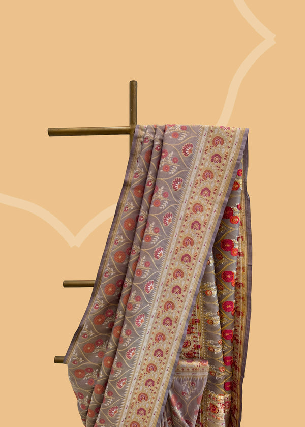 A lavender tissue by silk saree with a mehraab Meenakari design all over the body and border in zari and contrast maroon colour. Shop the best collection of authentic, handwoven, pure benarasi sarees with Roliana New Delhi