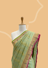 A pista green vertical stripe zari woven saree in dull gold with a vibrant meenakari paithani border and a hand-painted stripe pallu in multicolour..  Shop the best collection of authentic, handwoven, pure benarasi sarees with Roliana New Delhi