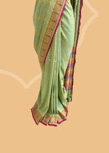 A pista green vertical stripe zari woven saree in dull gold with a vibrant meenakari paithani border and a hand-painted stripe pallu in multicolour..  Shop the best collection of authentic, handwoven, pure benarasi sarees with Roliana New Delhi