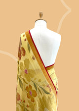 A lemon yellow khaddi Georgette saree with upada floral bootas all over which have detailed hand painted patterns all over and a contrast red kanni . Shop the best collection of authentic, handwoven, pure benarasi sarees with Roliana New Delhi