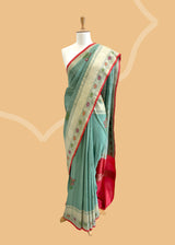 A patina green tussar Georgette saree with meenakari guldasta of flowers and a meenakari border and pallu.. A pure Banarasi wedding Sari Shop the best collection of authentic, handwoven, pure benarasi sarees with Roliana New Delhi