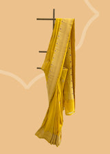A mustard yellow saree with delicate woven flowers and border in contrast meenakari colours. A pure Banarasi Sari Shop the best collection of authentic, handwoven, pure benarasi sarees with Roliana New Delhi