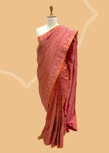 Pink silk saree in floral brocade weave with all over motifs and ornamental pallu with a delightful orange contrast kanni. pure Banarasi sari. Shop the best collection of authentic, handwoven, pure benarasi sarees with Roliana New Delhi