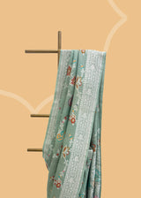 Sage green tussar georgette saree with a colourful meenakari jaal and silver zari bootis and border. Shop the best collection of authentic, handwoven, pure benarasi sarees with Roliana New Delhi