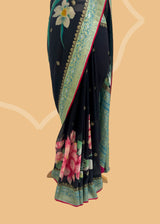 A beautiful Georgette weave saree with zari bootis and border and hand painted in vibrant bunches of pink flowers and green leaves with delicate sky blue lilies in between . A pure Banarasi wedding Sari Shop the best collection of authentic, handwoven, pure benarasi sarees with Roliana New Delhi