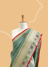 A patina green tussar Georgette saree with meenakari guldasta of flowers and a meenakari border and pallu.. A pure Banarasi wedding Sari Shop the best collection of authentic, handwoven, pure benarasi sarees with Roliana New Delhi