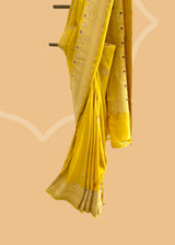 A mustard yellow saree with delicate woven flowers and border in contrast meenakari colours. A pure Banarasi Sari Shop the best collection of authentic, handwoven, pure benarasi sarees with Roliana New Delhi