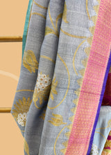 Grey saree with silver gold jaal of floral meenakari, offset with a wine border and pallu, and finished with a bright blue kanni. Shop the best collection of authentic, handwoven, pure benarasi sarees with Roliana New Delhi