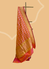 a traditional peach pink shot saree in silk with Sona roopa zari bootis and a chevron zari border and pallu. A pure Banarasi wedding Sari Shop the best collection of authentic, handwoven, pure benarasi sarees with Roliana New Delhi