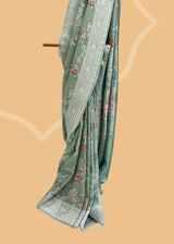 Sage green tussar georgette saree with a colourful meenakari jaal and silver zari bootis and border. Shop the best collection of authentic, handwoven, pure benarasi sarees with Roliana New Delhi