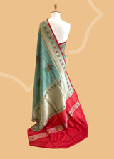 A patina green tussar Georgette saree with meenakari guldasta of flowers and a meenakari border and pallu.. A pure Banarasi wedding Sari Shop the best collection of authentic, handwoven, pure benarasi sarees with Roliana New Delhi