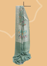 Sage green tussar georgette saree with a colourful meenakari jaal and silver zari bootis and border. Shop the best collection of authentic, handwoven, pure benarasi sarees with Roliana New Delhi