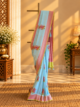 A fresh powder blue muga georgette saree with meenakari floral bootas dismissed off with a pink border and a fresh lime green kanni