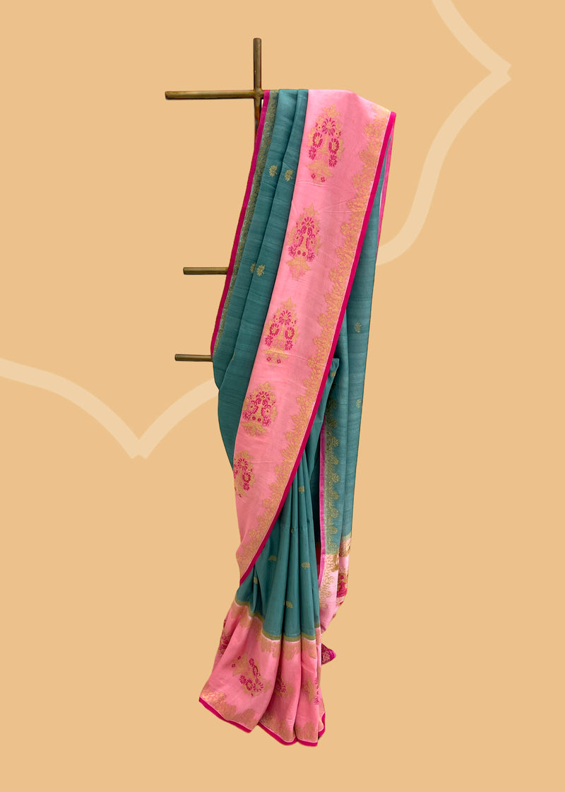 A beautiful teal colour saree with a contrast pink border in soft silk.  Shop the best collection of authentic, handwoven, pure benarasi sarees with Roliana New Delhi