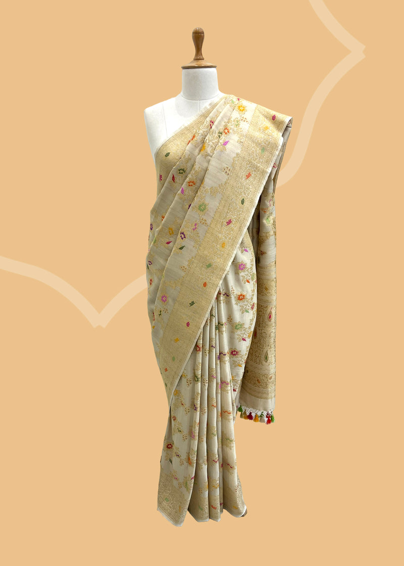  A natural being coloured saree in khaddi Georgette with interwining gold zari jaal and meenakari flower trellis jaal and an ornamental border and pallu.  Shop the best collection of authentic, handwoven, pure benarasi sarees with Roliana New Delhi