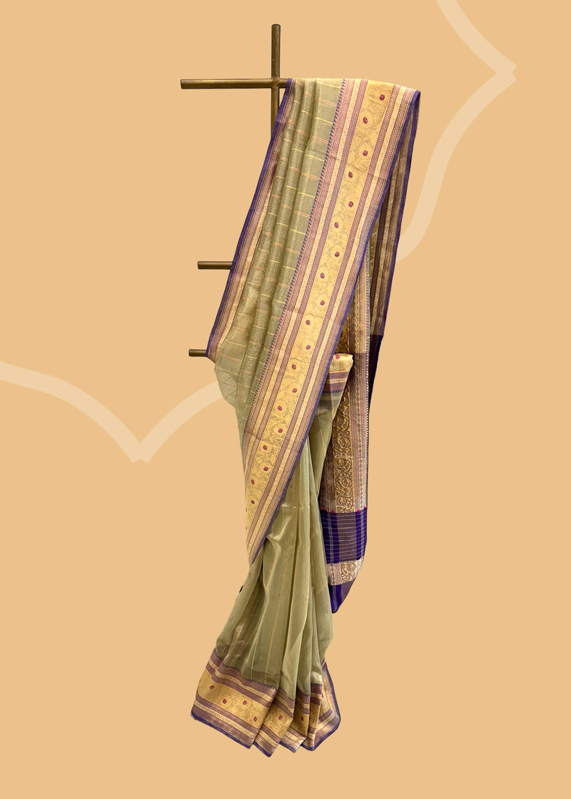 This benarasi handwoven cream saree features subtle gold bootis and a champagne shot color, complemented by a bright blue kanni and pallu. perfect for summer wedddings. Shop the best collection of authentic, handwoven, pure benarasi sarees with Roliana New Delhi