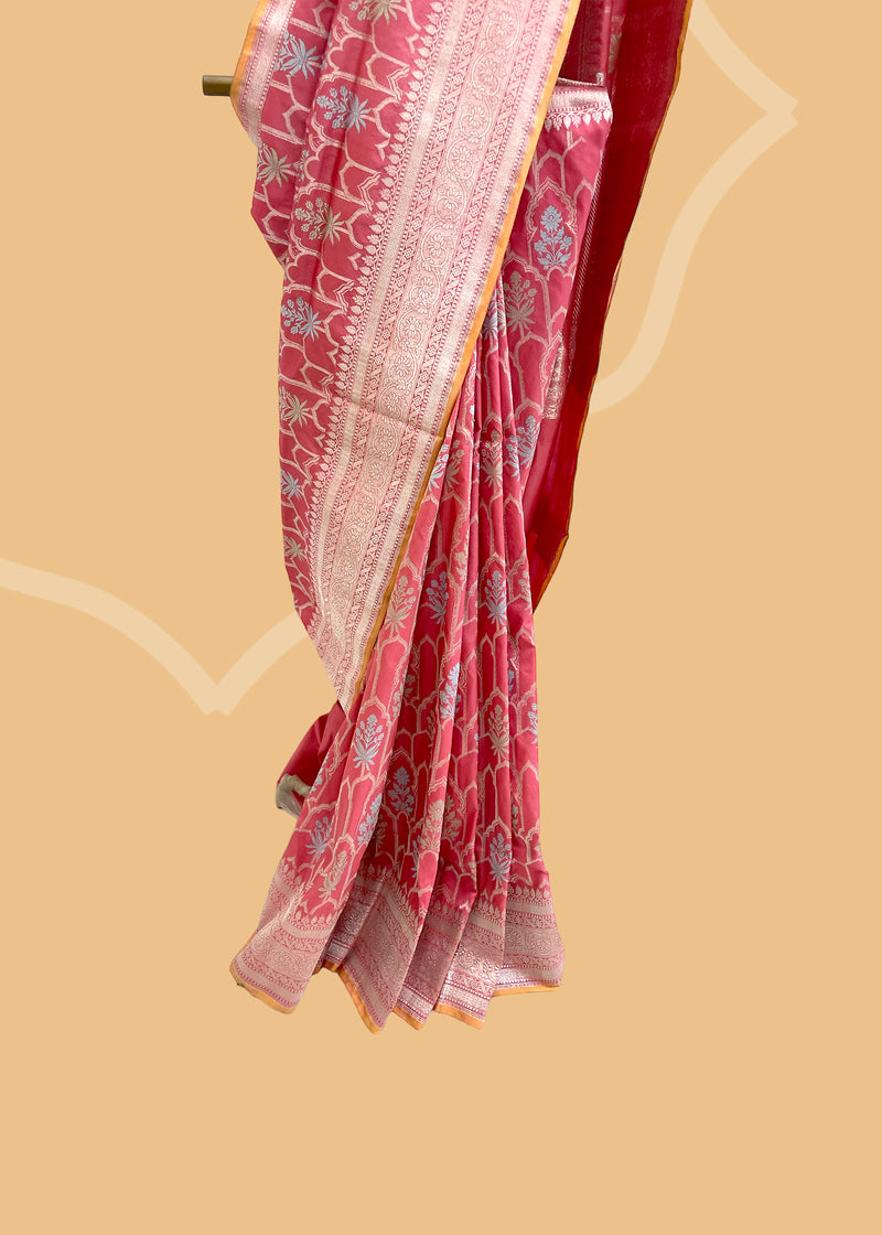 This exquisite saree features an elegant ektaara design in a beautiful salmon pink shade, embellished with powder blue and sage green motifs in an oriental jaal pattern. Shop the best collection of authentic, handwoven, pure benarasi sarees with Roliana New Delhi