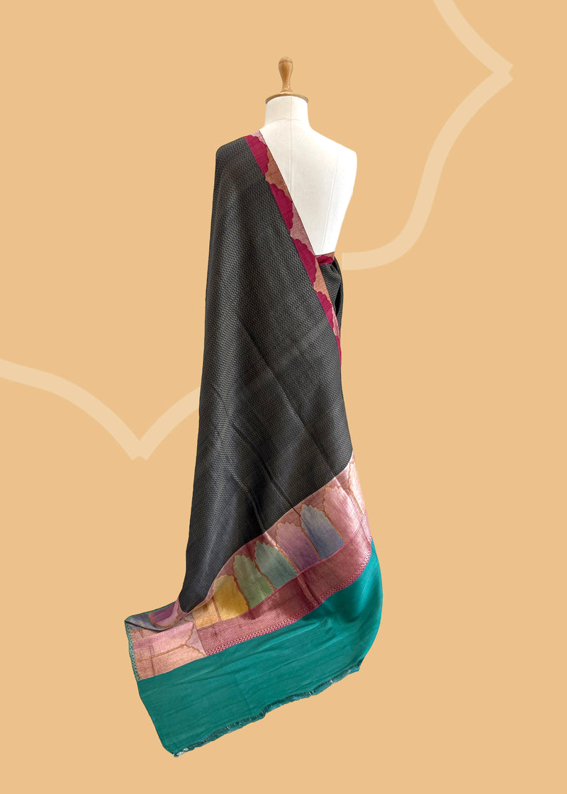 A charcoal grey chevron weave saree with handshaded mehraab border motifs. Shop the best collection of authentic, handwoven, pure benarasi sarees with Roliana New Delhi