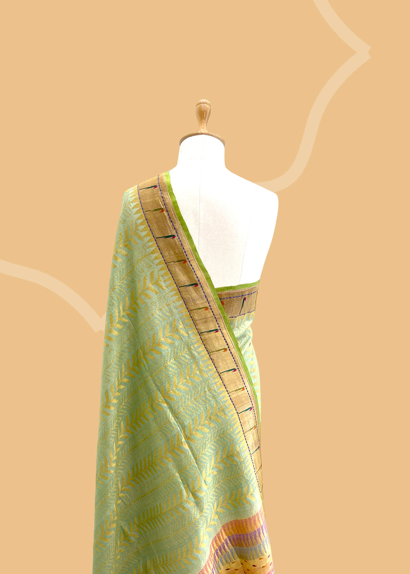 A pista green vertical stripe zari woven saree in dull gold with a vibrant meenakari paithani border and a hand-painted stripe pallu in multicolour..  Shop the best collection of authentic, handwoven, pure benarasi sarees with Roliana New Delhi