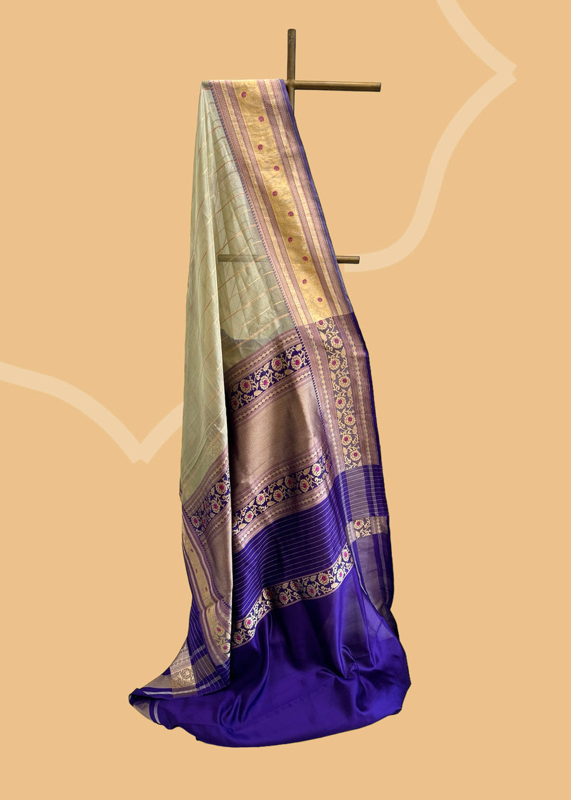 This benarasi handwoven cream saree features subtle gold bootis and a champagne shot color, complemented by a bright blue kanni and pallu. perfect for summer wedddings. Shop the best collection of authentic, handwoven, pure benarasi sarees with Roliana New Delhi