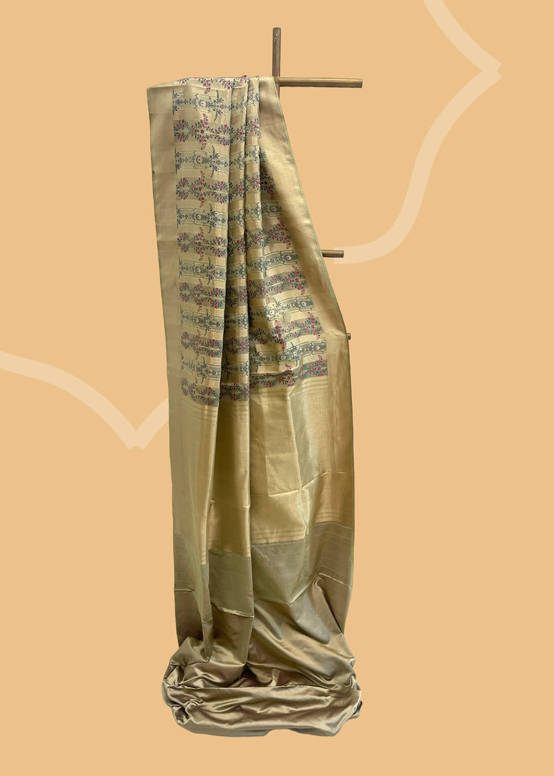This unique and stylish Ivory & Moss Green Tanchoi Silk Benarasi Saree from Roliana is crafted with an exquisite combination of tanchoi weave and delicate, pink bunches of small flowers.