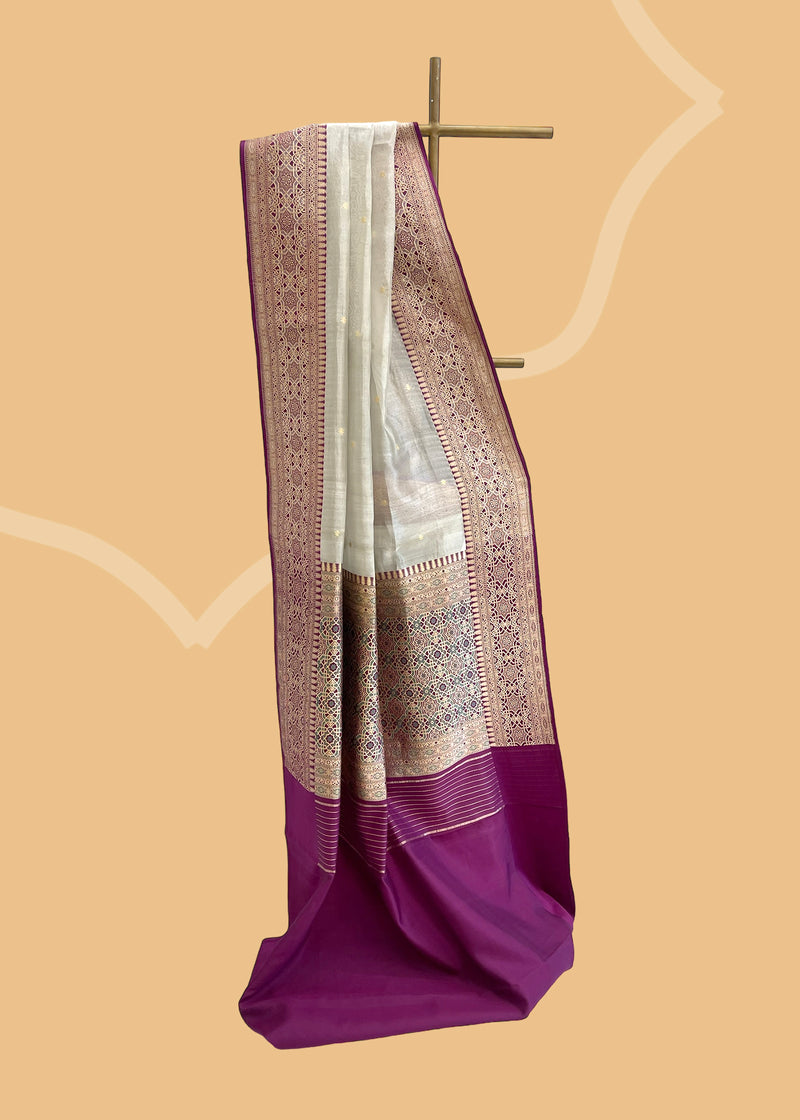 A silver tissue saree on very soft fabric with delicate woven zari booties and offset with a wine coloured jamali work border and pallu . Shop the best collection of authentic, handwoven, pure benarasi sarees with Roliana New Delhi