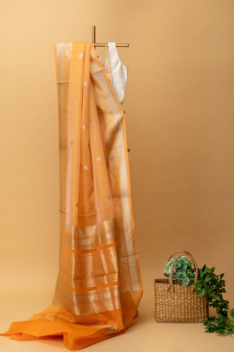 Orange pure kora handwoven banarasi saree with delicate woven bootis and floral border by Roliana Weaves.