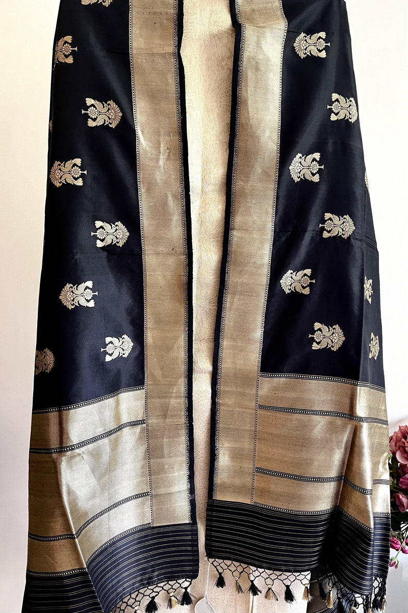 A black silk dupatta with peacock motifs woven, gold border by Roliana Weaves.