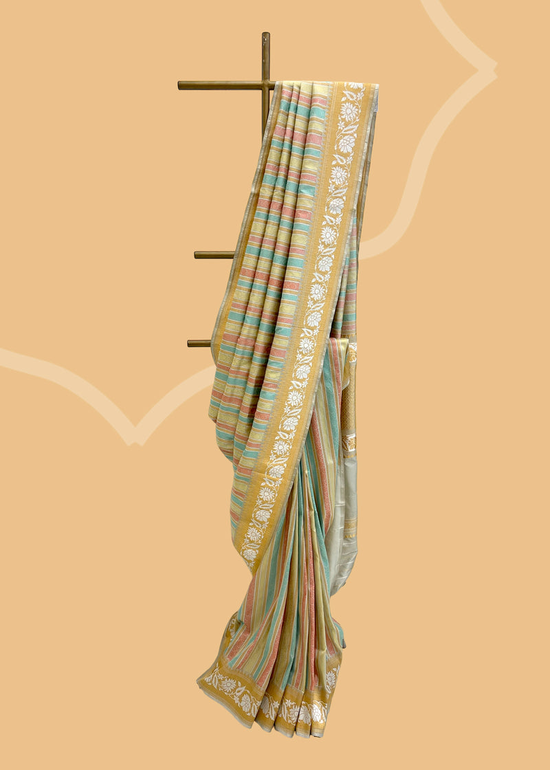 A silk tanchoi woven saree with pastel strips in light pink, green, firozi strips and a beautiful border of silver flowers.. A pure Banarasi wedding Sari Shop the best collection of authentic, handwoven, pure benarasi sarees with Roliana New Delhi