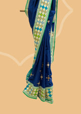 Navy blue phulkari weave booti saree with a striking green phulkari border and pallu. Shop the best collection of authentic, handwoven, pure benarasi sarees with Roliana New Delhi