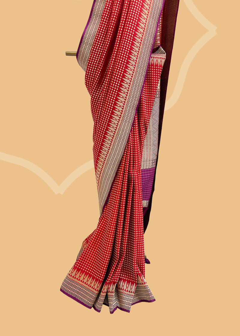 A flamboyant red woven satin silk saree with a beautiful contrast purple border and a chèvron pallu. Shop the best collection of authentic, handwoven, pure benarasi sarees with Roliana New Delhi