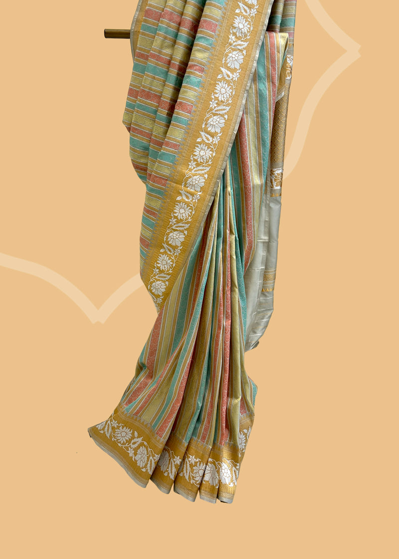 A silk tanchoi woven saree with pastel strips in light pink, green, firozi strips and a beautiful border of silver flowers.. A pure Banarasi wedding Sari Shop the best collection of authentic, handwoven, pure benarasi sarees with Roliana New Delhi