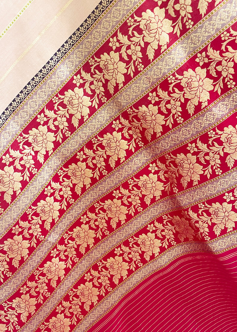 A soft peach gajji saree with vertical stripes in zari complemented by a Rani pink floral woven border and another golden yellow border for that extra special look. Shop the best collection of authentic, handwoven, pure benarasi sarees with Roliana New Delhi