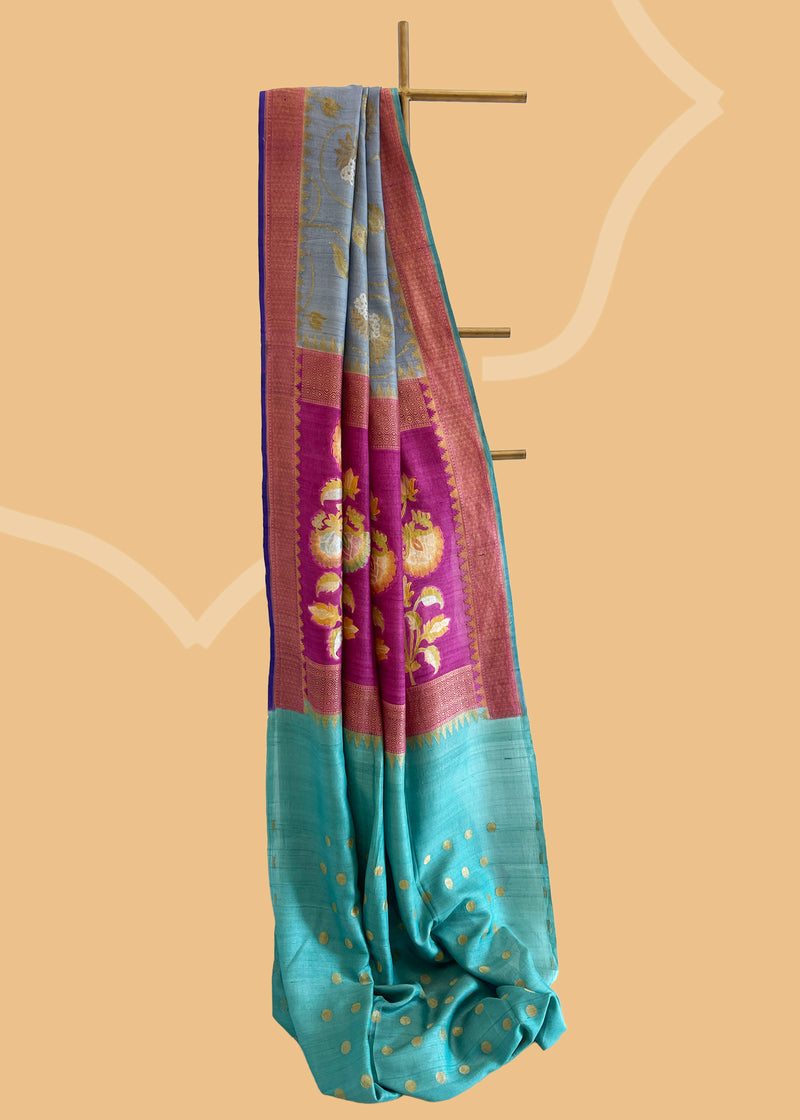 Grey saree with silver gold jaal of floral meenakari, offset with a wine border and pallu, and finished with a bright blue kanni. Shop the best collection of authentic, handwoven, pure benarasi sarees with Roliana New Delhi