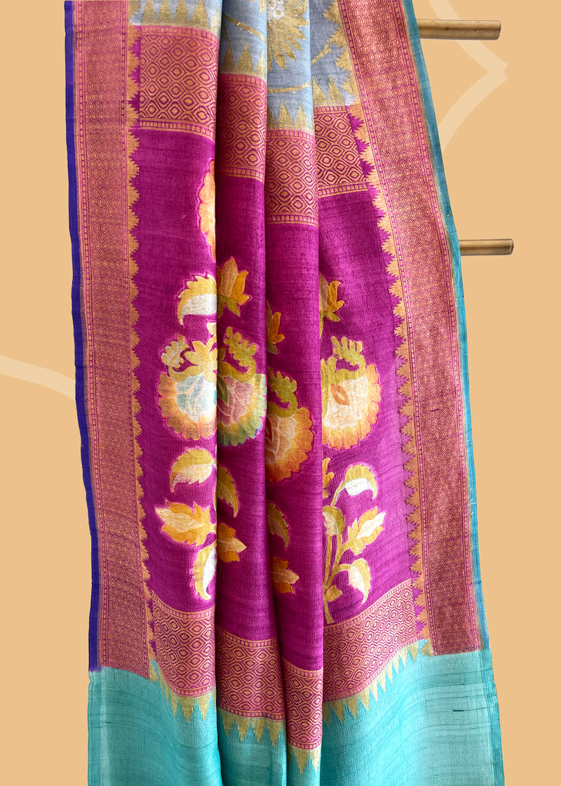 Grey saree with silver gold jaal of floral meenakari, offset with a wine border and pallu, and finished with a bright blue kanni. Shop the best collection of authentic, handwoven, pure benarasi sarees with Roliana New Delhi