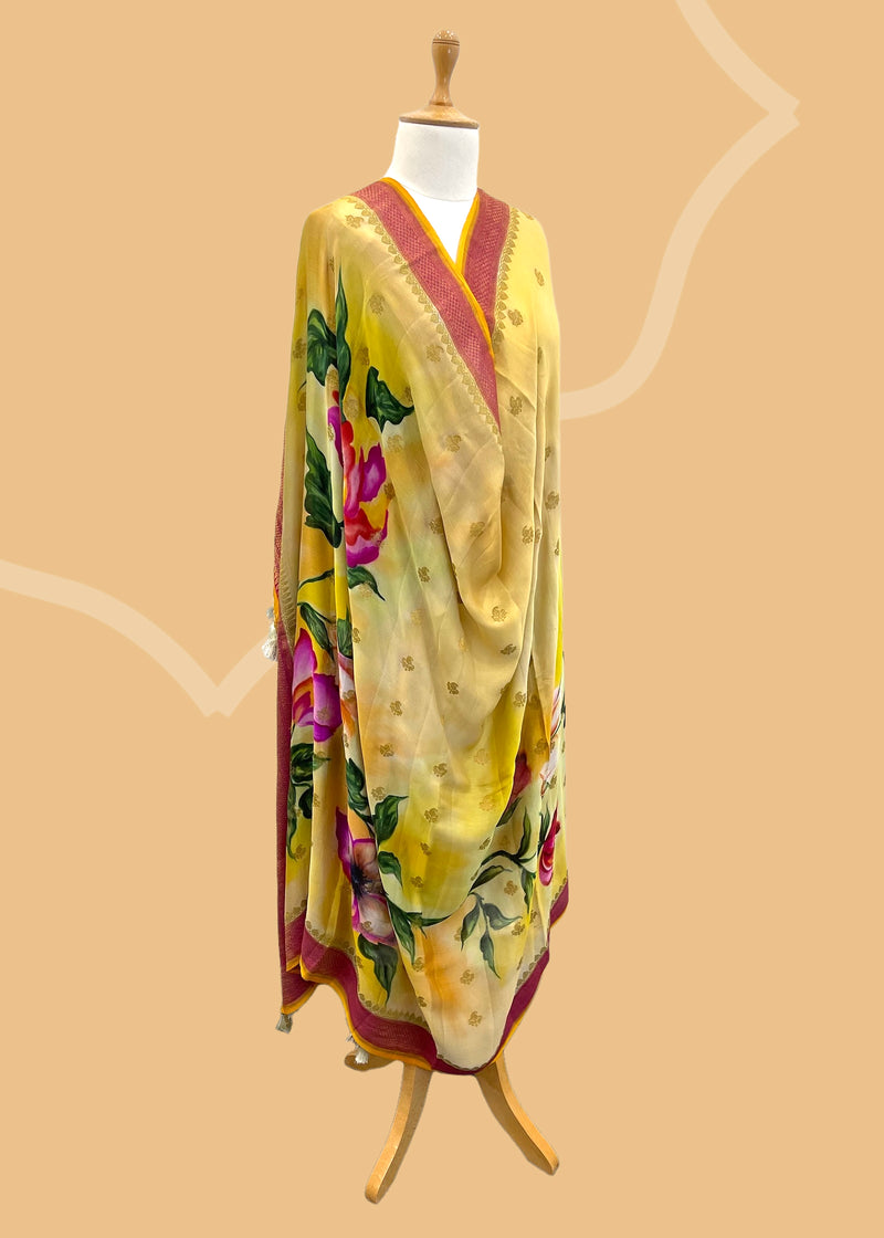 Pure silk benarasi dupatta in yellow with handpainted flowers by Roliana Weaves. Shop the best of Banarasi sarees, dupattas and lehengas at Roliana New Delhi